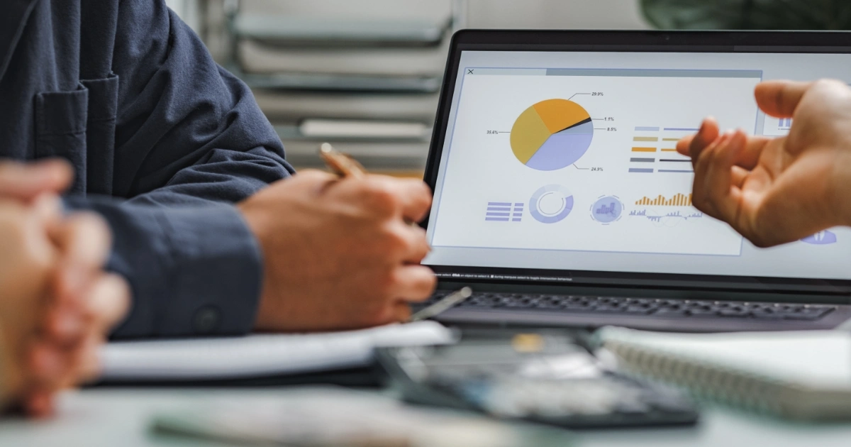 Laptop screen showing colorful charts and graphs during a business meeting.